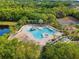 Aerial view of a resort-style pool and clubhouse surrounded by lush tropical landscaping at 437 Chantilly Trl, Bradenton, FL 34212