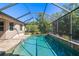 View of the screened-in in-ground pool and outdoor lush landscaping at 437 Chantilly Trl, Bradenton, FL 34212