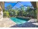 View of the screened-in in-ground pool and outdoor lush landscaping at 437 Chantilly Trl, Bradenton, FL 34212