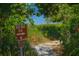 Trail leading to the beach with signage indicating the Beach Walk Trail amidst lush greenery at 4610 13Th W St, Palmetto, FL 34221