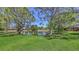 Beautiful backyard with lush green lawn, mature trees, and a tranquil pond at 4832 Carrington Cir, Sarasota, FL 34243