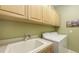 Bright laundry room with overhead cabinets, utility sink, and modern washing machine at 4832 Carrington Cir, Sarasota, FL 34243