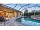 Inviting screened-in pool area with beautiful landscaping and a comfortable outdoor dining setup at 4832 Carrington Cir, Sarasota, FL 34243
