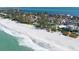 Aerial view of condos with red tile roofs along a white sand beach with a blue ocean on a clear day at 5055 Gulf Of Mexico Dr # 414, Longboat Key, FL 34228