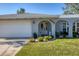 Charming home exterior with arched entryway, well-manicured lawn, and attached garage at 5206 18Th E Ave, Bradenton, FL 34208