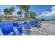 Beautiful beach view with stacked blue beach chairs, palm trees and condo buildings in the background on a clear day at 5920 Midnight Pass Rd # 406, Sarasota, FL 34242