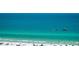 Beach scene showcases clear turquoise water, boats, people swimming and relaxing on the white sand beach at 5920 Midnight Pass Rd # 406, Sarasota, FL 34242