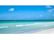 Scenic beach view of clear turquoise waters, waves, with a paddle boarder and an egret by the shore at 5920 Midnight Pass Rd # 406, Sarasota, FL 34242