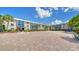 Condo exterior with large parking area, palm trees and blue skies at 5920 Midnight Pass Rd # 406, Sarasota, FL 34242