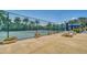 Tennis area with tables and chairs under blue umbrellas, surrounded by flowers and trees at 5920 Midnight Pass Rd # 406, Sarasota, FL 34242