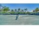 Scenic tennis court surrounded by lush greenery and tall palm trees on a bright day at 5920 Midnight Pass Rd # 406, Sarasota, FL 34242