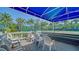 Relaxing deck area with seating, views of the tennis court, and tropical trees at 5920 Midnight Pass Rd # 406, Sarasota, FL 34242