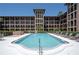 Community pool with lounge chairs and well-maintained landscaping in front of the condo complex at 6100 Gulfport S Blvd # 117, Gulfport, FL 33707