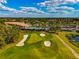 Stunning aerial view of a golf course with a clubhouse, pool, and lush landscaping under a beautiful sky at 6524 Willowshire Way, Bradenton, FL 34212