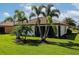 Picturesque backyard features lush green grass and mature palm trees surrounding the private screened in lanai at 6524 Willowshire Way, Bradenton, FL 34212