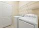 Functional laundry room with white appliances and shelving for storage at 6524 Willowshire Way, Bradenton, FL 34212