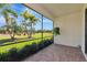 Screened patio with brick flooring overlooks a lush green lawn with landscaped palm trees and blue skies at 6524 Willowshire Way, Bradenton, FL 34212