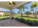 Relaxing screened lanai with brick flooring and a view of palm trees and lush green lawn at 6524 Willowshire Way, Bradenton, FL 34212