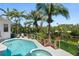 Serene backyard featuring a pool, spa, tropical foliage, and waterfront views at 7118 Hawks Harbor Cir, Bradenton, FL 34207