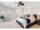 A primary bedroom showcasing a king bed, ceiling fan and sitting chair by the windows at 7118 Hawks Harbor Cir, Bradenton, FL 34207