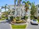 Stunning two-story white home with tile roof, lush landscaping, and a circular driveway with palm trees at 7118 Hawks Harbor Cir, Bradenton, FL 34207
