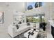 Open-concept living room features white sectional, high ceilings and expansive windows with tropical views at 7118 Hawks Harbor Cir, Bradenton, FL 34207
