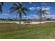 View of the golf course with mature palm trees enhancing the lush landscaping under a blue sky at 7155 Boca Grove Pl # 102, Lakewood Ranch, FL 34202