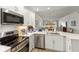 Modern kitchen with white cabinets and stainless steel appliances overlooks the open-concept living space at 7155 Boca Grove Pl # 102, Lakewood Ranch, FL 34202