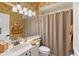 Well-lit bathroom with bamboo wallpaper, classic vanity, and a shower with a tan curtain at 7805 Allen Robertson Pl, Sarasota, FL 34240