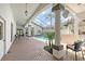 A screened-in pool area with brick flooring, seating, and views of the home's exterior at 7805 Allen Robertson Pl, Sarasota, FL 34240