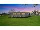 Well-maintained backyard and the side exterior of single story home against a sunset background at 80 Liles St, Terra Ceia, FL 34250