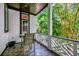 Outdoor balcony with patterned tile flooring, decorative railings and abundant greenery views from the surrounding trees at 103 Park Ave, Anna Maria, FL 34216