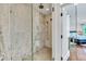 Luxurious bathroom features a glass shower with marble tile surround, mosaic tile floor, and view into the main bedroom at 103 Park Ave, Anna Maria, FL 34216