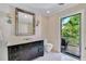 Elegant bathroom features a black vanity with a white countertop, a large mirror, and access to the outdoor porch at 103 Park Ave, Anna Maria, FL 34216