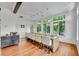 Bright dining room boasts hardwood floors, white chairs, and large windows showcasing verdant outdoor scenery at 103 Park Ave, Anna Maria, FL 34216