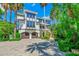 Stately three-story home featuring a brick driveway, lush landscaping, and a two-car garage at 103 Park Ave, Anna Maria, FL 34216