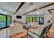 Bright living room featuring white sofas, wood beam ceilings, fireplace, and access to a deck with beautiful outdoor views at 103 Park Ave, Anna Maria, FL 34216
