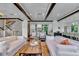 Spacious living room features hardwood floors, white couches, coffered ceiling, and an open view of kitchen and dining areas at 103 Park Ave, Anna Maria, FL 34216