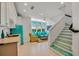 Open-concept living room and kitchen area with unique blue refrigerator, stairs, and cozy seating space at 103 Park Ave, Anna Maria, FL 34216