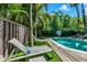 Backyard pool featuring multiple lounge chairs, tropical plants, and privacy fence at 103 Park Ave, Anna Maria, FL 34216