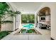 Backyard pool and spa surrounded by lush landscaping and an outdoor living space at 103 Park Ave, Anna Maria, FL 34216