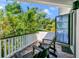 Outdoor porch features red brick floors, green chairs, and tropical greenery at 103 Park Ave, Anna Maria, FL 34216