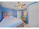 Bright blue bedroom with bed, ceiling fan, wood-look tile flooring, and painted dresser at 130 E Seminole Dr, Venice, FL 34293