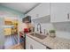 Well-lit kitchen with white cabinets, granite countertops, stainless appliances, and stylish tile backsplash at 130 E Seminole Dr, Venice, FL 34293