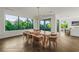 Dining area boasts modern chandelier, a wooden table with seating, and a wall of windows with lush outdoor views at 135 Grant Dr, Sarasota, FL 34236