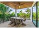 Covered patio featuring modern outdoor dining set, ceiling fan, and tropical landscaping views at 135 Grant Dr, Sarasota, FL 34236