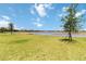 Backyard with a lush green lawn, a pond, and trees, with other homes in the distance at 14914 15Th E St, Parrish, FL 34219