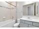 Well-lit bathroom with tub, neutral tile, and a modern gray vanity at 14914 15Th E St, Parrish, FL 34219