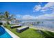 Beautiful waterfront backyard with lounge chairs, palm tree, and dock extending into the ocean at 201 Bay N Dr, Bradenton Beach, FL 34217