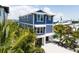 Exterior view of a charming blue home surrounded by lush palm trees and a coastal view at 201 Bay N Dr, Bradenton Beach, FL 34217